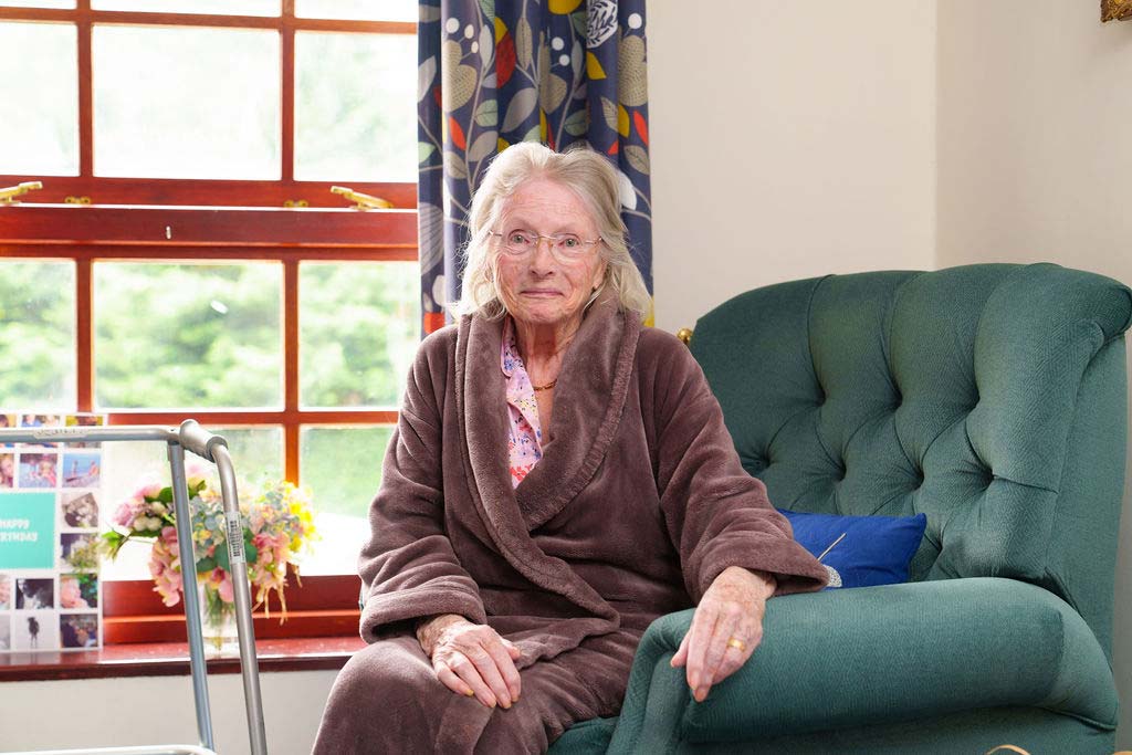 Happy Resident Sitting in Teal Armchair